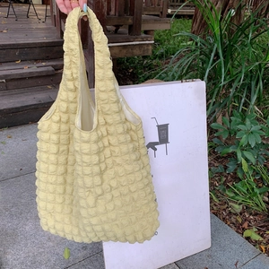 Macro detail of the light yellow popcorn texture and flexible pleated fabric on the tote bag