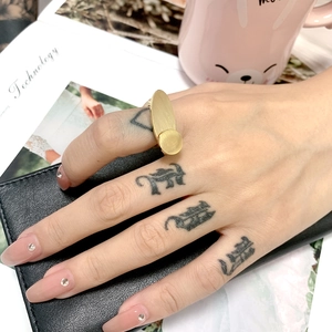 Close-up of gold titanium steel ring with oval and round plates on a model's finger