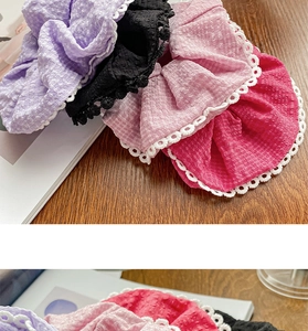 Close-up of fabric hair scrunchies with white lace edges in purple, pink and black colors