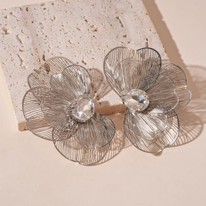 Detail of silver hollow flower earrings with sparkling rhinestone center on stone base