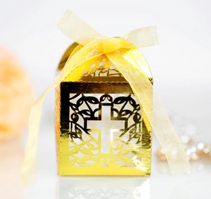 Close-up of golden laser-cut wedding favor box with cross design and ribbon