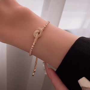 Close-up of gold plated knot bracelet with cubic zirconia on model wrist