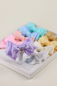 Détail de barrettes à nœuds en ruban de satin plissé aux couleurs pastel assorties