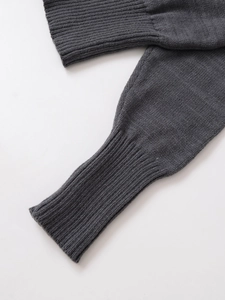 Dettaglio dei polsini in maglia grigio scuro con texture a coste molto rifinita