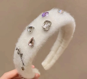 Close-up of white plush headband with colorful heart-shaped gemstones and rose pendant