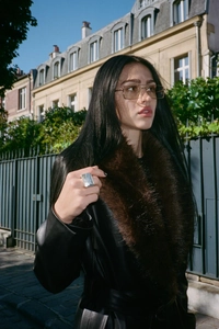 Detail of a black leather coat with a brown fur collar and metallic accessories