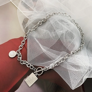 Detalle del collar de cadena plateada con cierre OT y colgantes grabados Love y Grace