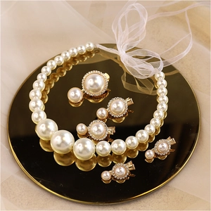 Elegant bridal set with white pearl necklace and gold rhinestone hair clips on mirror tray