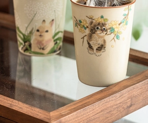Close-up of a Ru Kiln ceramic cup with a hand-painted cat on a flower branch