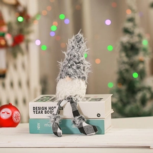 Detail of plush grey Christmas gnome with long checkered legs on a festive book stack