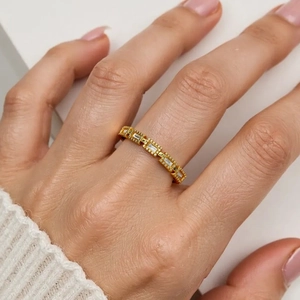 Detail of 18K gold plated ring with emerald-cut zircon stones on model's finger
