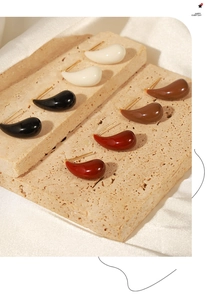 Detail showing elegant teardrop enamel earrings in white, black, coffee and dark red colors