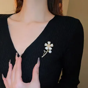 Broche fleur dorée élégante avec pétales en nacre, centre en zircon et perle pendante