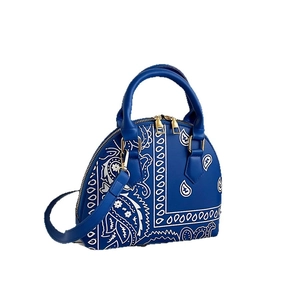 Blue bandana print shell handbag with golden hardware on a clean white background