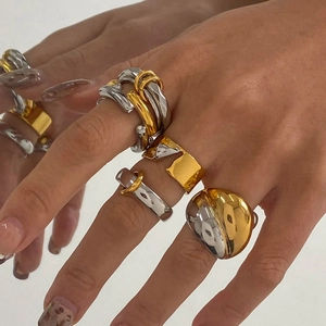 Close-up of industrial style mixed gold and silver chunky rings on model's fingers