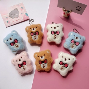 Close-up of colorful plush bear pendants with pink bows and metal bead chains