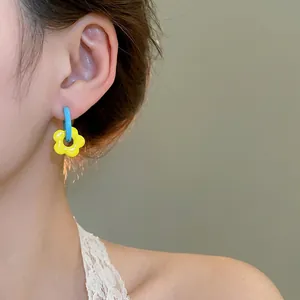 Vibrant blue and yellow flower drop earrings shown on a model for casual daily wear