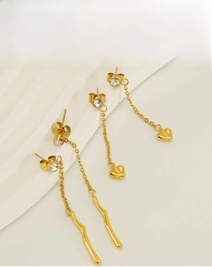 Close-up of golden tassel earrings with heart pendants and sparkling zircon stones