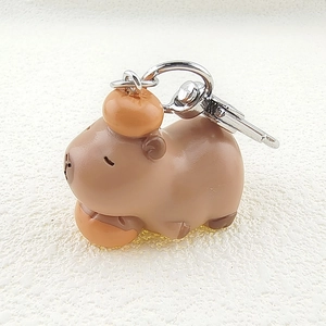 Close-up of cute 3D resin Capybara keychain with orange charm and silver metal hook