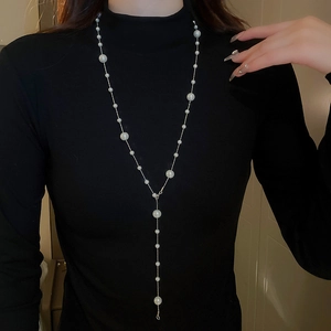 Close-up of Y-shaped pearl tassel necklace worn on a black turtleneck sweater