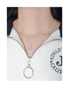 Close-up of a silver pretzel heart pendant necklace worn on a white athletic sweatshirt