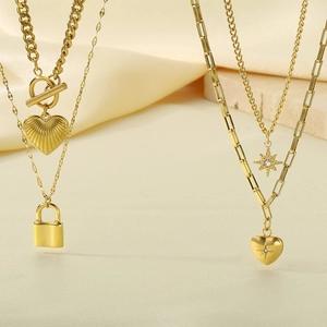 Detail of layered gold titanium necklace with heart, lock and starburst pendants