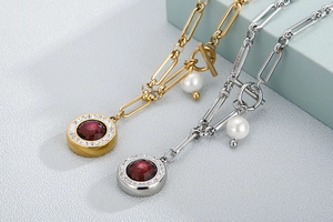 Detailed view of gold and silver necklaces with red gemstone and pearl charms