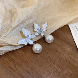 Détail de boucles d'oreilles papillon en perles argentées sur bois vintage