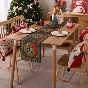 Christmas table runner with wreath and Merry Christmas text on wooden dining table