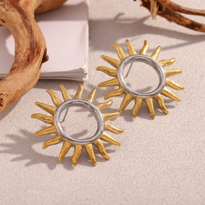 Detail of hollow sun earrings with 18k gold plated finish and two-tone metal design