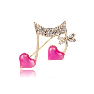 Detailaufnahme der goldenen Musiknoten-Brosche mit rosa Herzen und funkelnden Kristallen