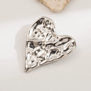 Detailed view of silver heart brooch with textured lava finish on white background