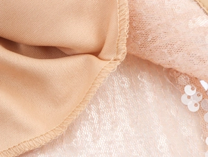 Vue macro du tissu à paillettes champagne et doublure avec couture surjetée précise