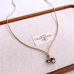 Close-up of vintage brown enamel gourd pendants on gold woven cord over a fabric tray