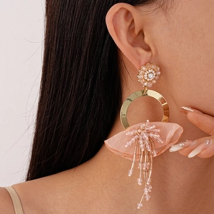 Close-up of pink beaded flower earrings with gold hoop and long tassel detail
