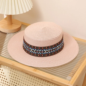 Close-up of light pink straw hat with colorful ethnic embroidery on wooden shelf