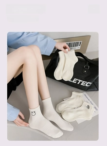 Close-up of white cotton ankle socks featuring cute cartoon embroidery and soft knit texture