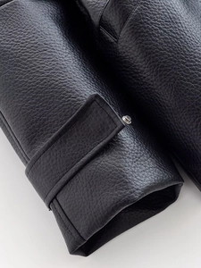 Detailed macro view of black faux leather jacket cuff with silver metal buckle