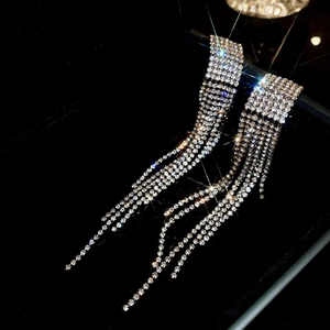 Macro close-up of luxury long tassel silver needle earrings with shimmering rhinestones