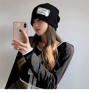 Close-up of a stylish black knitted beanie with a minimalist patch label for women