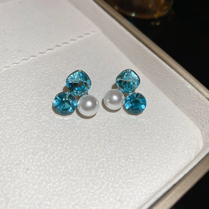 Macro shot of sky blue crystal and pearl cluster stud earrings with silver plating