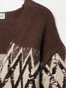 Close-up of brown knit sweater featuring ivory wavy patterns and shimmering sequins