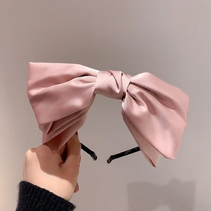 Dettaglio di fascia per capelli in raso rosa con fiocco grande e trama di seta lucida