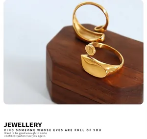Polished wave-shaped gold open rings displayed on a premium hexagonal wooden jewelry stand