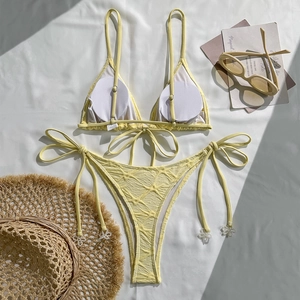 Flat lay of yellow halter bikini with ribbed fabric and delicate white flower beads