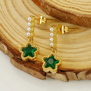 Boucles d'oreilles étoile en or avec zircon vert et perles sur un socle en bois