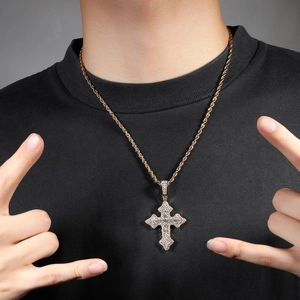 Gros plan d'un collier chaîne torsadée dorée avec pendentif croix serti de zircons