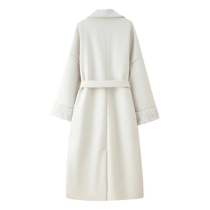 Detail view of the back of a white wool coat with elegant fur-trimmed cuffs and waist belt