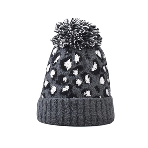 Detail of knitted leopard print beanie featuring a fluffy faux fur pompom in dark grey