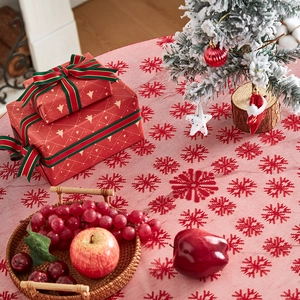 Detail view of red Christmas tablecloth with white snowflake patterns and festive decor